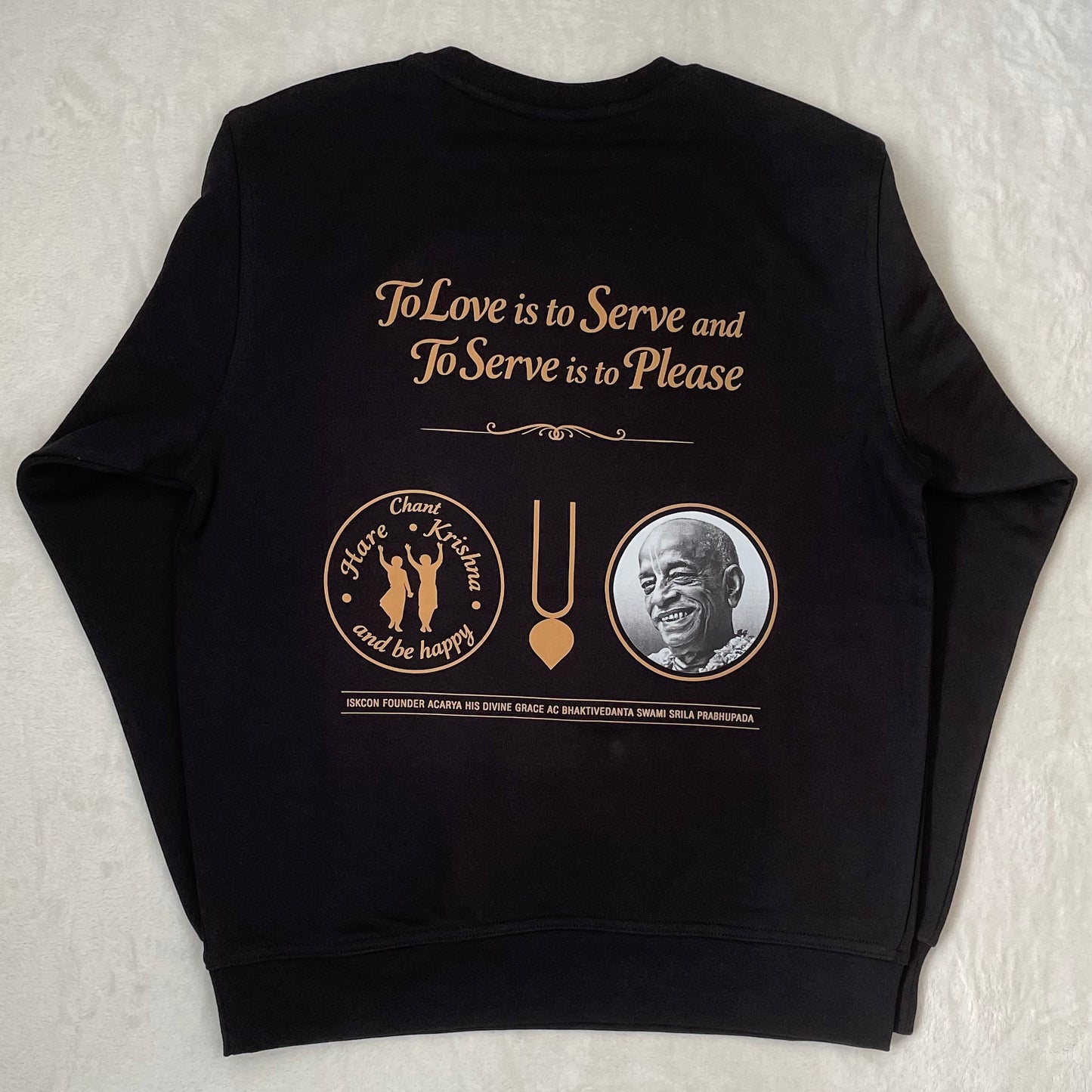 Black sweatshirt with gold text and graphics on a textured white background